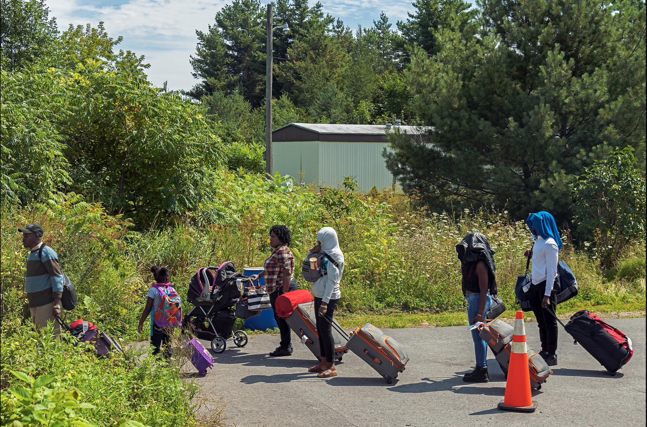 Image 1: A family of asylum seekers crossing the US-Canada border at <I>Roxham Road</I> in Aug. 2017. Photo: D. Case.